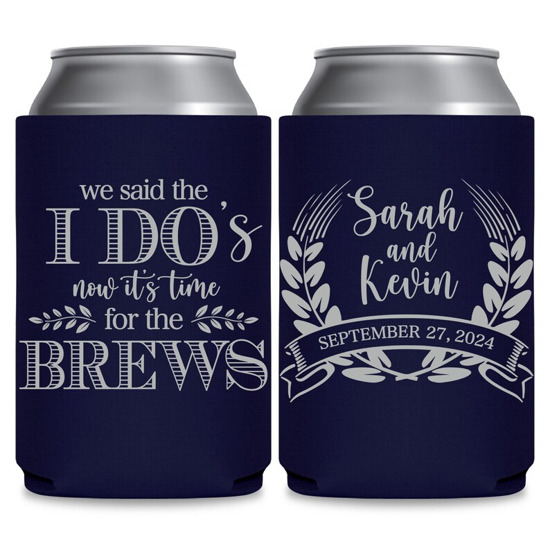 May include: Two navy blue can coolers with white text. The cooler on the left says 'we said the I DO'S now it's time for the BREWS'. The cooler on the right says 'Sarah and Kevin SEPTEMBER 27, 2024' with a wreath design around the names.