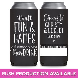 May include: Two black and white can coolers. The left cooler has the text 'it's all FUN & GAMES until someone loses their DRINK.' The right cooler has the text 'Cheers to CHRISTY & ROBERT 08.13.2024' with a heart symbol and 'THIS DRINK BELONGS TO' with a blank space for a name.