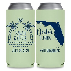 May include: Two green can coolers with a white top. The left cooler has a palm tree design with the text 'Sarah & Chris' and 'July 29, 2024'. The right cooler has an outline of the state of Florida with a heart in the panhandle and the text 'Destin Florida' and '#YOURHASHTAG'.