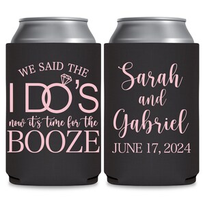 May include: Two black can coolers with pink text. The left cooler has the text 'We said the I DO'S now it's time for the BOOZE.' The right cooler has the text 'Sarah and Gabriel JUNE 17, 2024.'
