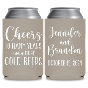 May include: Two tan can coolers with white text. The left cooler says 'Cheers to many years and a lot of cold beers'. The right cooler says 'Jennifer and Brandon October 13, 2024'.