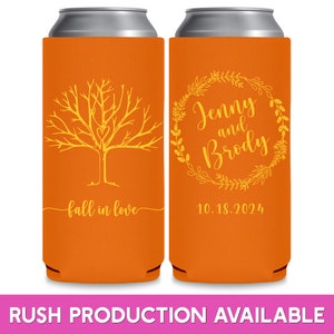 May include: Two orange can coolers with yellow designs. The left cooler has a tree with a heart in the branches and the text 'fall in love'. The right cooler has a wreath with the text 'Jenny and Brody' and the date '10.18.2024'.