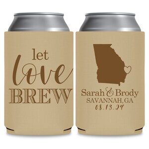 May include: Two brown and beige can coolers. The cooler on the left has the text 'let love BREW' in brown. The cooler on the right has a brown outline of the state of Georgia with a heart in the center, and the text 'Sarah & Brody SAVANNAH, GA 08.13.24' in brown.