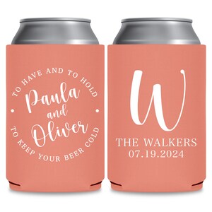 May include: Two coral colored can coolers with white text. The first cooler says 'To have and to hold Paula and Oliver to keep your beer cold.' The second cooler says 'W The Walkers 07.19.2024.'