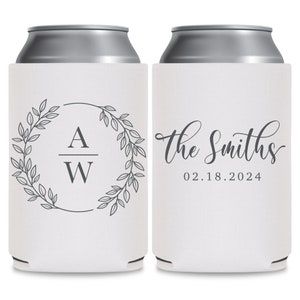 May include: Two white can coolers with a gray design. The cooler on the left has a wreath with leaves and the initials 'A W' inside. The cooler on the right has the text 'The Smiths' in cursive and the date '02.18.2024'.