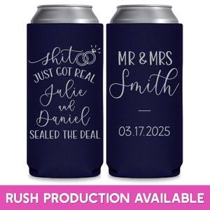 May include: Two navy blue can coolers with white text. The left cooler says 'shit just got real Julie and Daniel sealed the deal' with two rings and a diamond. The right cooler says 'MR & MRS Smith 03.17.2025'.