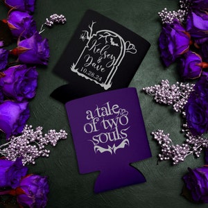 May include: Two purple and black can coolers with white text. One cooler has a tombstone design with the text 'Kelsey & Dave 10.28.24'. The other cooler has the text 'a tale of two souls'.