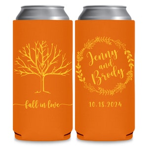 May include: Two orange can coolers with yellow designs. One cooler has a tree with a heart in the branches and the text 'fall in love'. The other cooler has a wreath with the text 'Jenny and Brody' and the date '10.18.2024'.