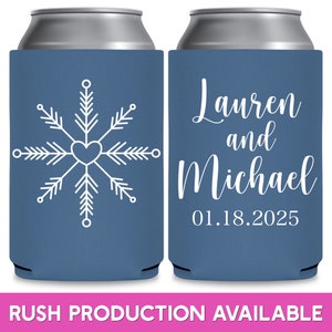 May include: Two blue can coolers with white text and designs. The left cooler has a snowflake design with a heart in the center. The right cooler has the text 'Lauren and Michael 01.18.2025'.