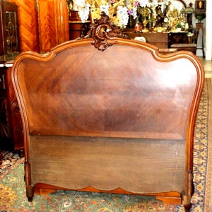 May include: A vintage wooden headboard with a carved design and a dark brown finish. The headboard is in good condition and has a classic French style.