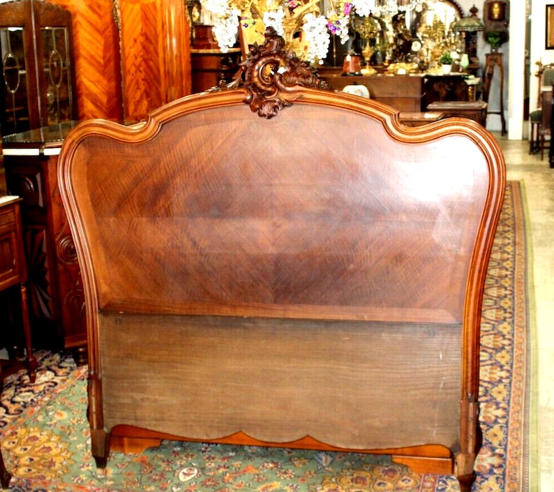 May include: A vintage wooden headboard with a carved design and a dark brown finish. The headboard is in good condition and has a classic French style.
