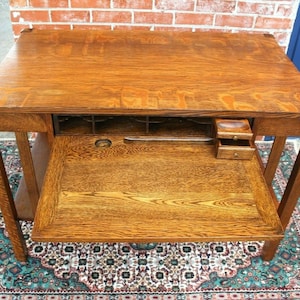 May include: A vintage wooden desk with a drop-down writing surface and multiple drawers. The desk is made of solid oak and has a rich brown finish.