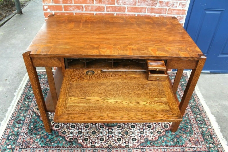 May include: A vintage wooden desk with a drop-down writing surface and multiple drawers. The desk is made of solid oak and has a rich brown finish.