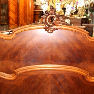 May include: A wooden headboard with a carved design and a rich brown finish. The headboard is made of wood with a decorative pattern.