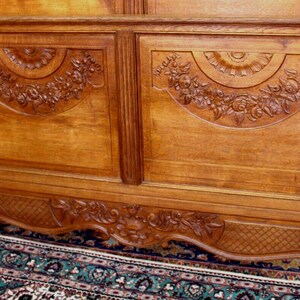 May include: A carved wooden headboard featuring intricate floral designs. The headboard is crafted from light brown wood and has a traditional style.