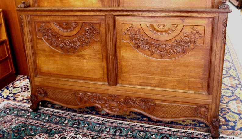 May include: A carved wooden headboard featuring intricate floral designs. The headboard is crafted from light brown wood and has a traditional style.