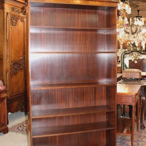 May include: A tall, dark wood bookcase with six shelves. The bookcase has a rich, reddish-brown finish with visible wood grain. The shelves are evenly spaced, and the piece has a classic, traditional design. The bookcase is a substantial piece of furniture.