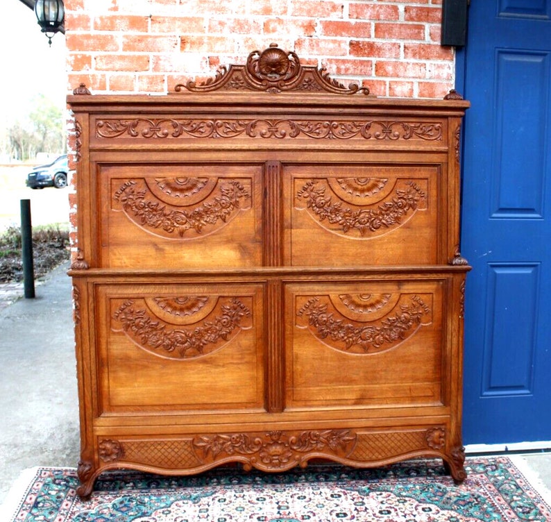 May include: A large, intricately carved wooden headboard with a floral design. The headboard is made of light brown wood and has a raised, ornate top.