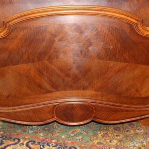 May include: A wooden headboard with a curved top and intricate carvings. The headboard is made of dark wood with a rich grain pattern.