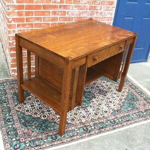 May include: A vintage wooden desk with a single drawer and a lower shelf. The desk is made of dark wood with a natural finish and has a simple, elegant design.
