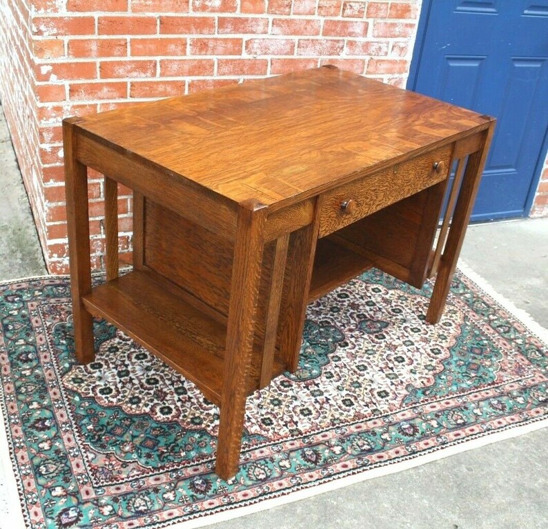 May include: A vintage wooden desk with a single drawer and a lower shelf. The desk is made of dark wood with a natural finish and has a simple, elegant design.