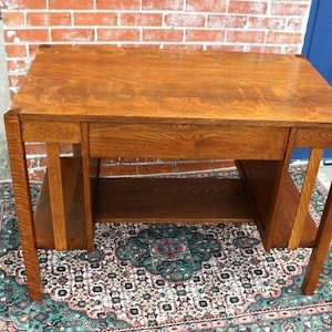 May include: A vintage wooden desk with a single drawer and open shelves. The desk is made of solid wood with a rich brown finish. It has a simple, elegant design and would be a great addition to any home office.