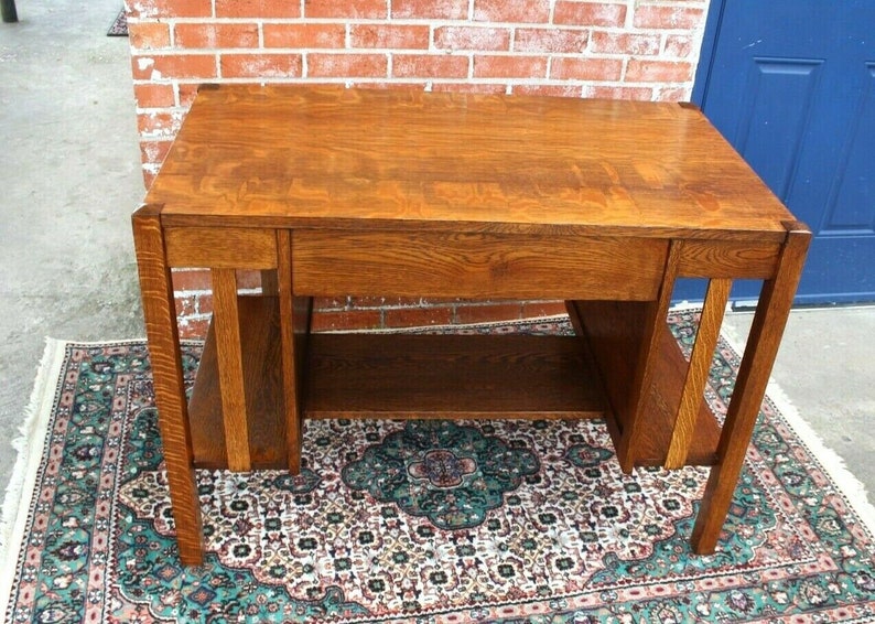 May include: A vintage wooden desk with a single drawer and open shelves. The desk is made of solid wood with a rich brown finish. It has a simple, elegant design and would be a great addition to any home office.