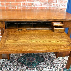 May include: A vintage wooden desk with a drop-down drawer and a small drawer on the right side. The desk has a dark wood finish and is in good condition.