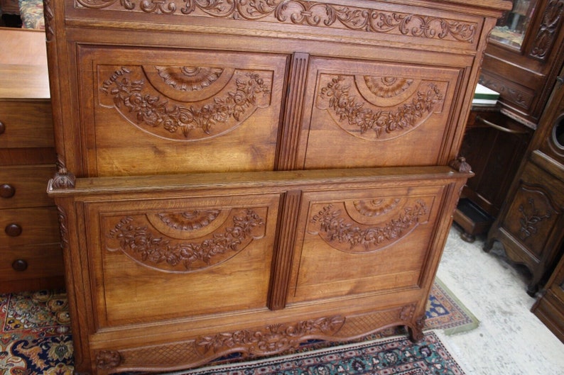 May include: A vintage wooden armoire with intricate carvings. The armoire has four doors with carved floral designs and a decorative top.