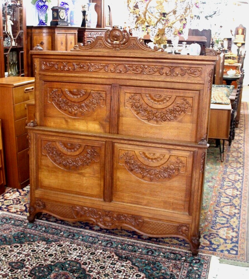 May include: A large, intricately carved wooden headboard with a decorative top and four panels. The headboard is made of light brown wood and features floral and scrollwork designs.