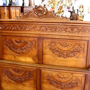 May include: A large, intricately carved wooden headboard with a decorative top and four panels. The headboard is made of a rich, dark wood and features floral and scrollwork designs.
