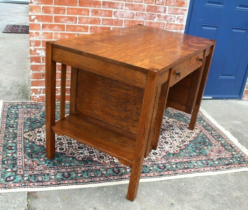 May include: A vintage wooden desk with a dark brown finish. The desk has a single drawer on the right side and a shelf below the desktop. The desk is sitting on a patterned rug.
