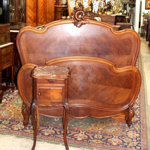 May include: A carved wooden headboard with a curved design and a matching nightstand with a marble top. The headboard and nightstand are both in a rich brown color.