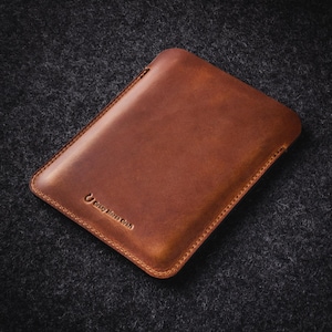 Puede incluir: Una funda rectangular de cuero marr&oacute;n con bordes cosidos. La funda tiene una superficie lisa y un logotipo en relieve que dice "Crazy Horse Craft". El cuero tiene un tono rico y c&aacute;lido, y el dise&ntilde;o general es minimalista y funcional.