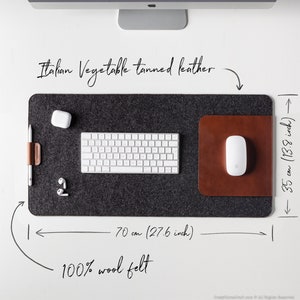 May include: A gray felt desk mat with a brown leather mousepad. The mat measures 27.6 inches wide and 13.8 inches long. It is made of 100% wool felt and has a leather border. The text "Italian Vegetable tanned leather" is written above the mat.