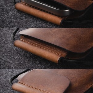 May include: A brown leather phone case with a stitched edge and a black cord. The case is designed to hold a smartphone securely.