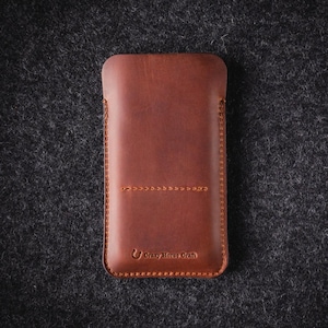 May include: A brown leather phone case with a stitched design and the text "Crazy Horse Craft" embossed on the bottom.