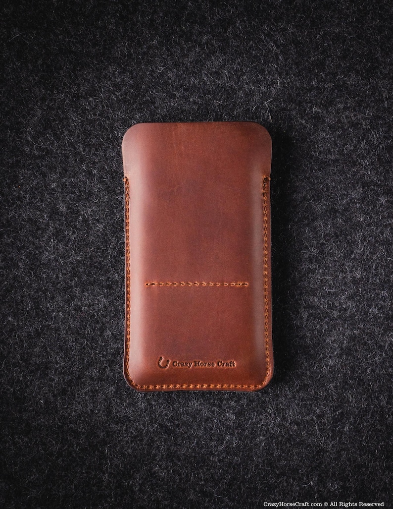 May include: A brown leather phone case with a stitched design and the text "Crazy Horse Craft" embossed on the bottom.