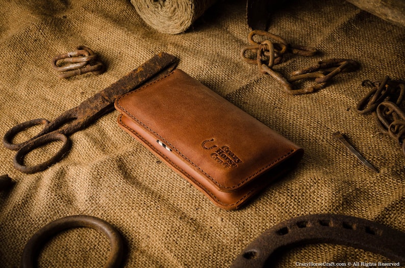 May include: A brown leather wallet with a stitched design and the text "Crazy Horse Craft" embossed on the front.