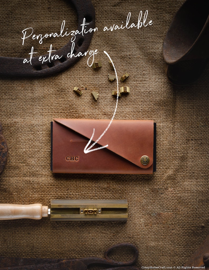 May include: A brown leather wallet with a flap closure and a metal button. The wallet has the initials "CHC" embossed on the front. The wallet is on a burlap background with metal tools and letters.