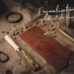 May include: A brown leather journal with a brass tool and a set of brass letter stamps. The journal has the alphabet printed on the cover. The text "Personalization available at extra charge!" is written on a white background.
