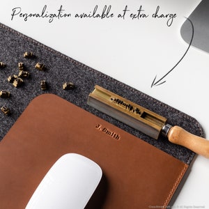 May include: A brown leather desk mat with a gray felt backing. The mat has a personalized inscription that reads "J. Smith". A metal letter stamping tool and a wooden handle are also visible.