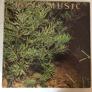 May include: A vintage vinyl record album cover featuring a close-up of green foliage against a dark background. The album title "ROXY MUSIC" is printed in white letters across the top of the cover.