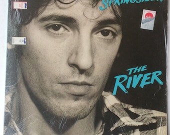 May include: Album cover for Bruce Springsteen's "The River." The image features a black and white portrait of Springsteen with the album title in turquoise and the artist's name in turquoise. The background is black.