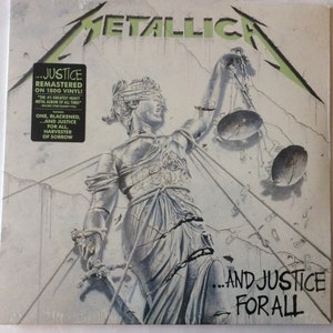 May include: A vinyl record cover for the Metallica album "...And Justice For All". The cover features a black and white illustration of a blindfolded woman holding a broken scale. The album title is written in black and white text at the bottom of the cover.