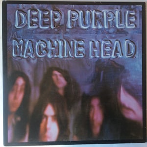 May include: A vintage vinyl record album cover featuring the band Deep Purple. The album title "Machine Head" is printed in large, bold letters on a blue and purple background. The band members are blurred in the background.
