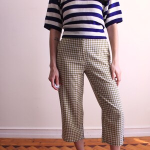 Pu&ograve; includere: Un top a maniche corte a righe blu navy e bianche &egrave; abbinato a pantaloni a quadri verde oliva e bianchi. I pantaloni sono tagliati alla caviglia. Un outfit casual, adatto all'uso quotidiano.