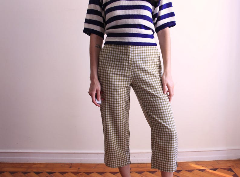 Pu&ograve; includere: Un top a maniche corte a righe blu navy e bianche &egrave; abbinato a pantaloni a quadri verde oliva e bianchi. I pantaloni sono tagliati alla caviglia. Un outfit casual, adatto all'uso quotidiano.