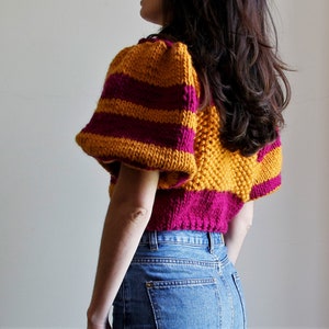 May include: A cropped sweater with yellow and burgundy stripes and puffed sleeves.