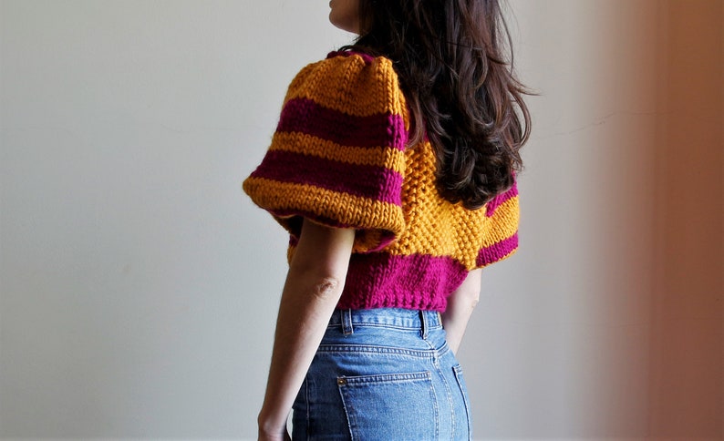 May include: A cropped sweater with yellow and burgundy stripes and puffed sleeves.